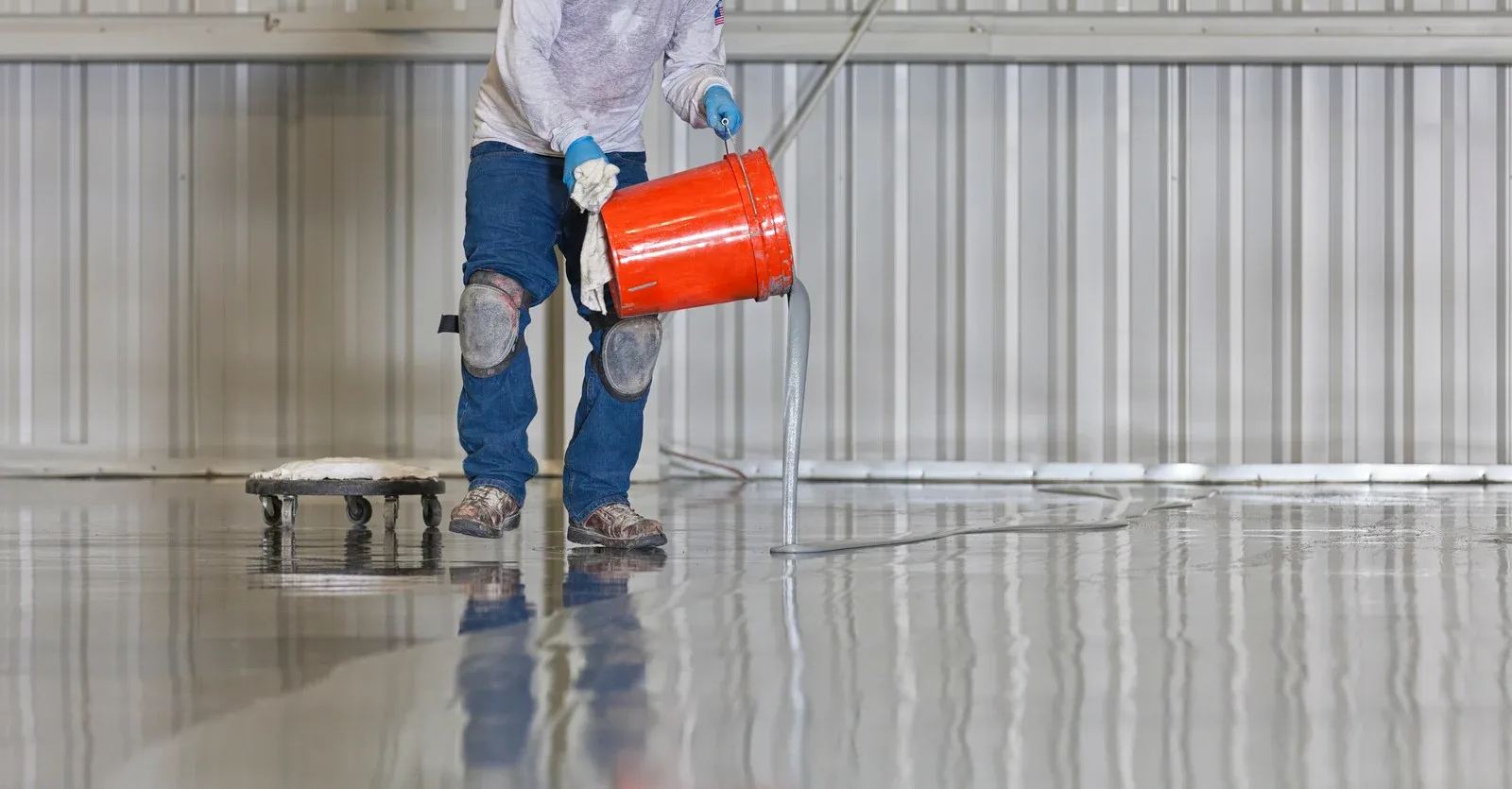 Interior of a white, empty industrial space with a polished gray floor and a raised platform.