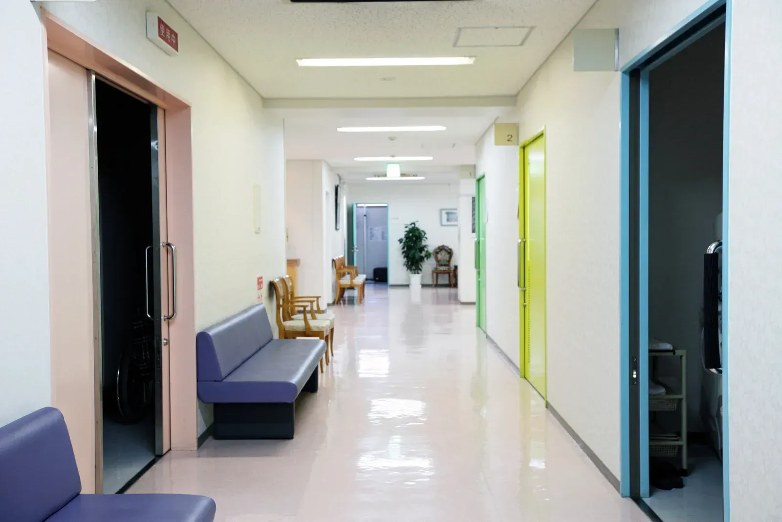 A hallway in a building with doors on each side, including one open to a room.
