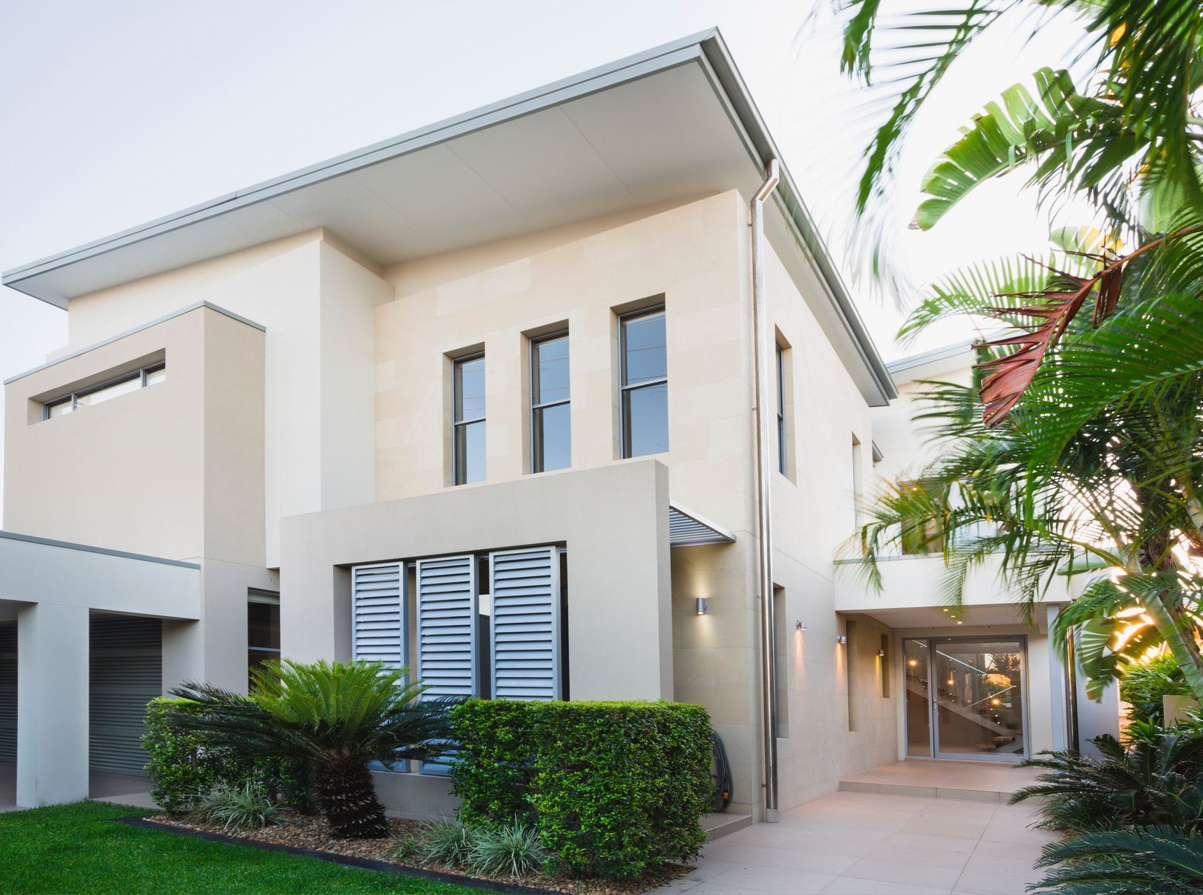 A large modern white house with a lot of windows.