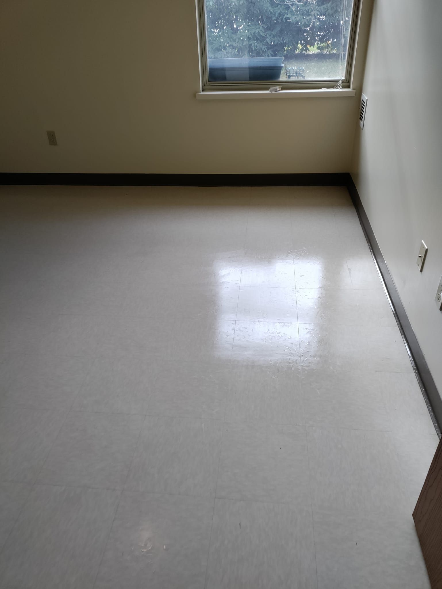 An empty room with a window and a white floor