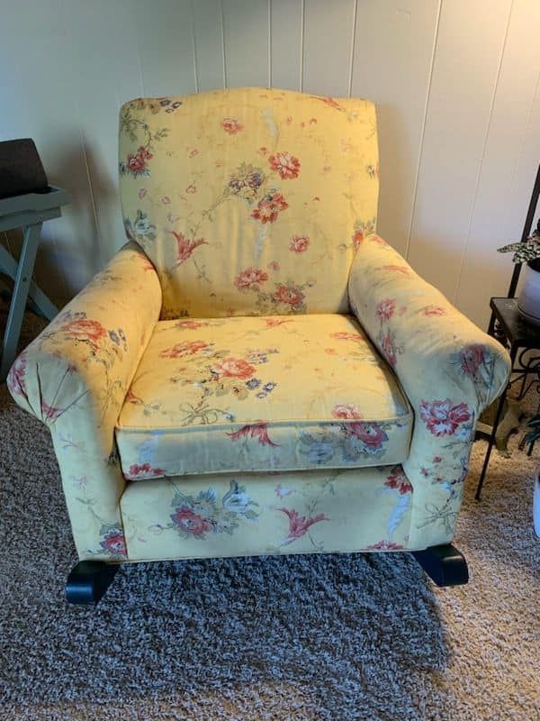A yellow floral chair is sitting on a carpet in a living room.