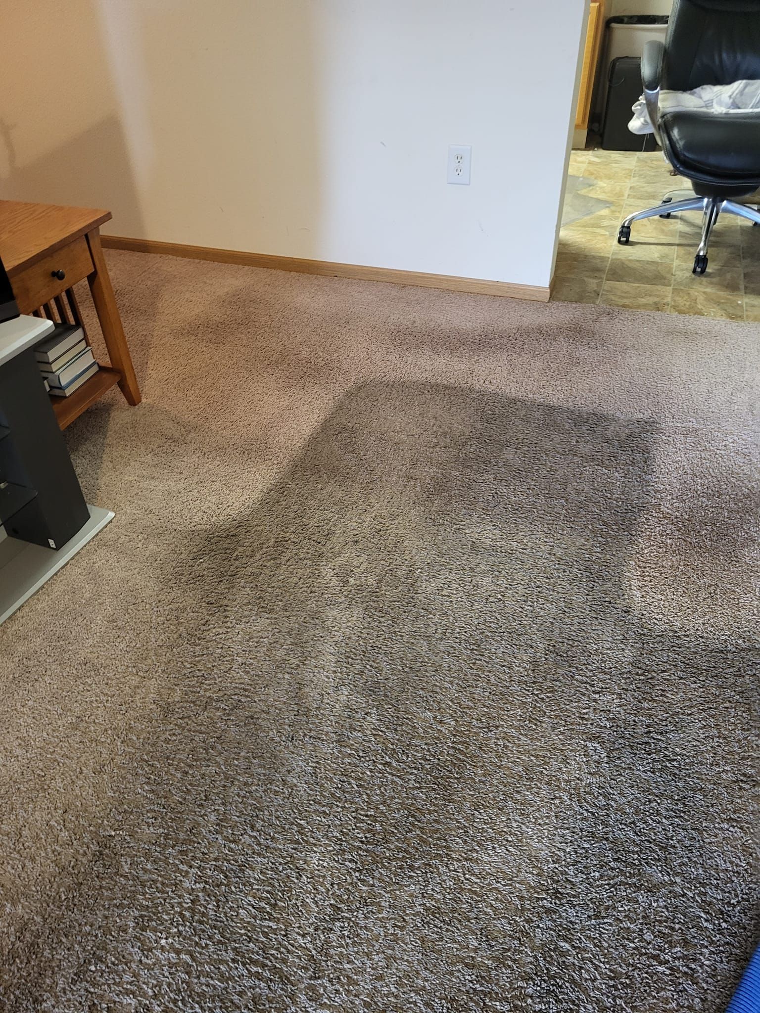 A living room with a carpeted floor and a chair.