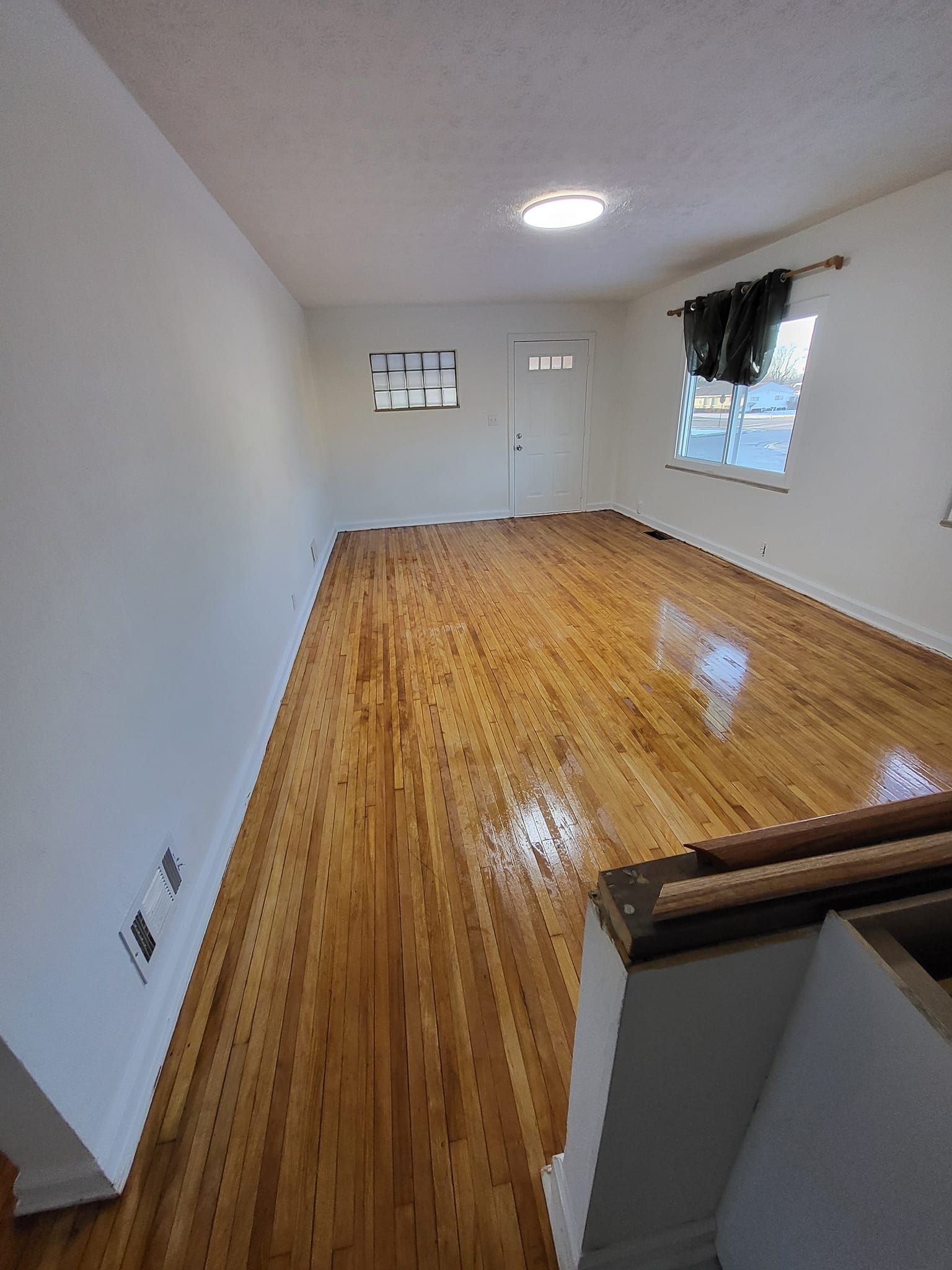 A living room with hardwood floors and white walls.