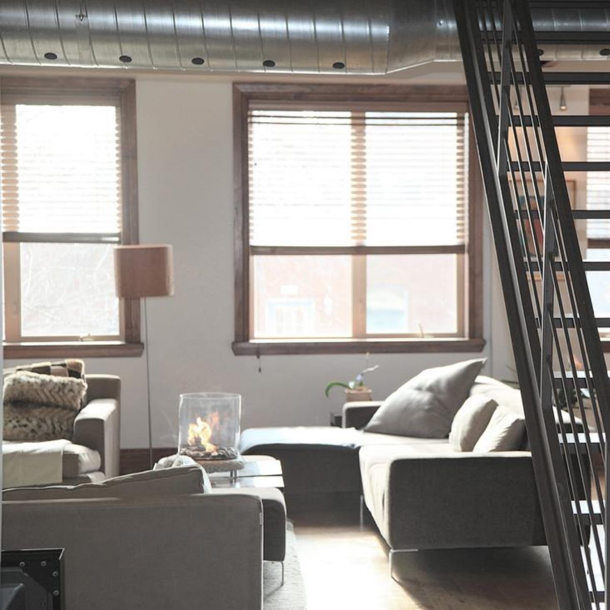 Living room with windows, a staircase, and a couch. Natural light illuminates the space.