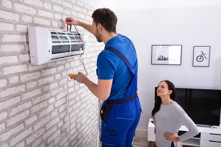 man repairing the split type air conditioner while lady watching him