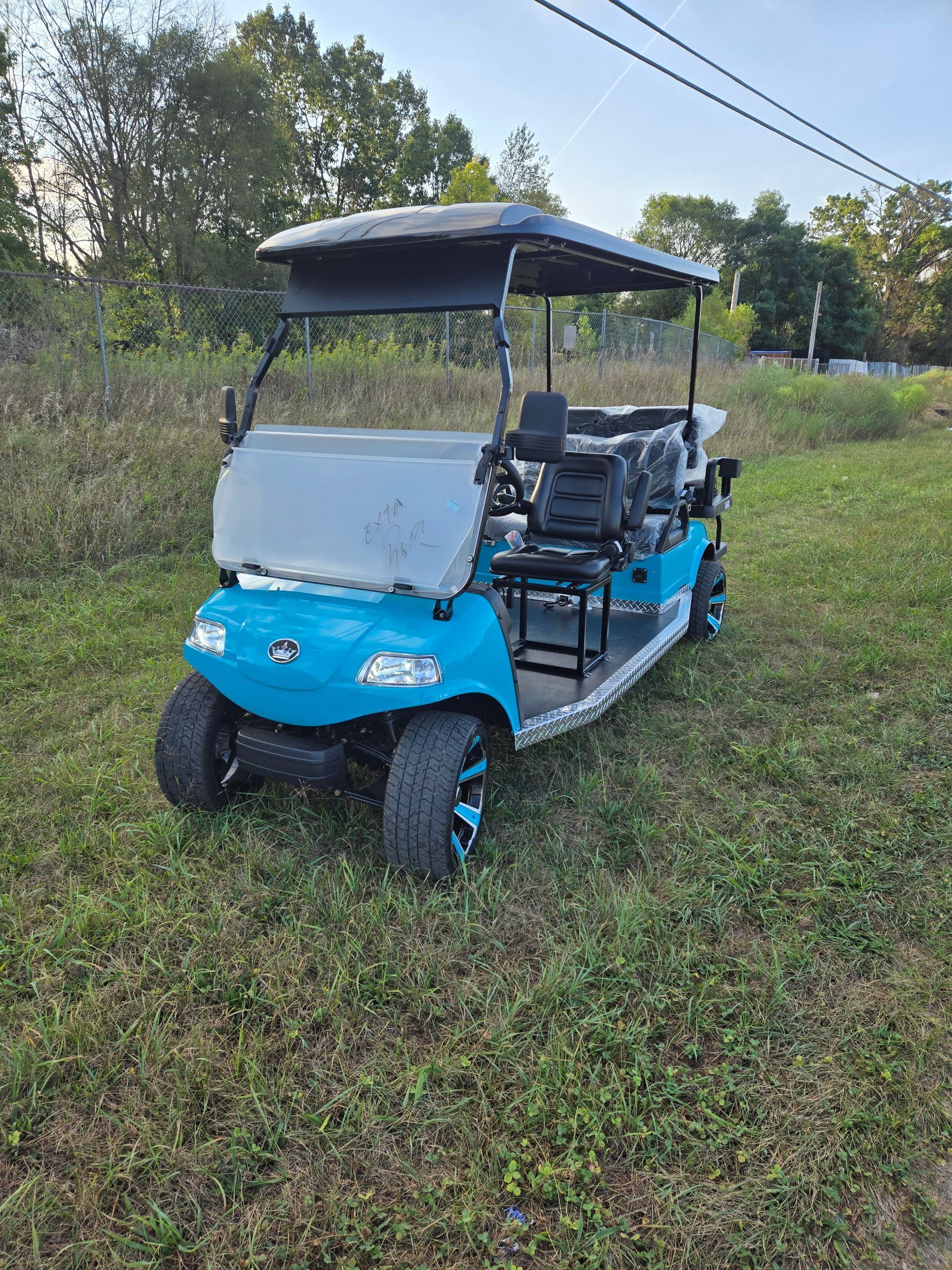 A blue golf cart is parked in a grassy field.