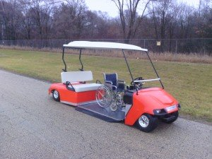 An orange golf cart with a wheelchair attached to it
