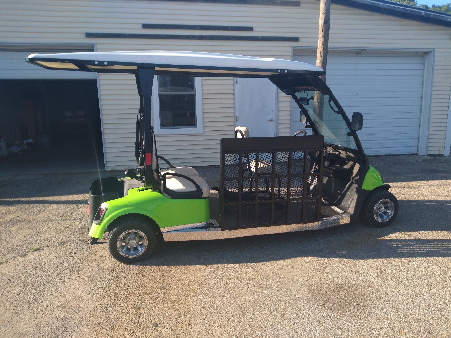 A green golf cart is parked in front of a garage.
