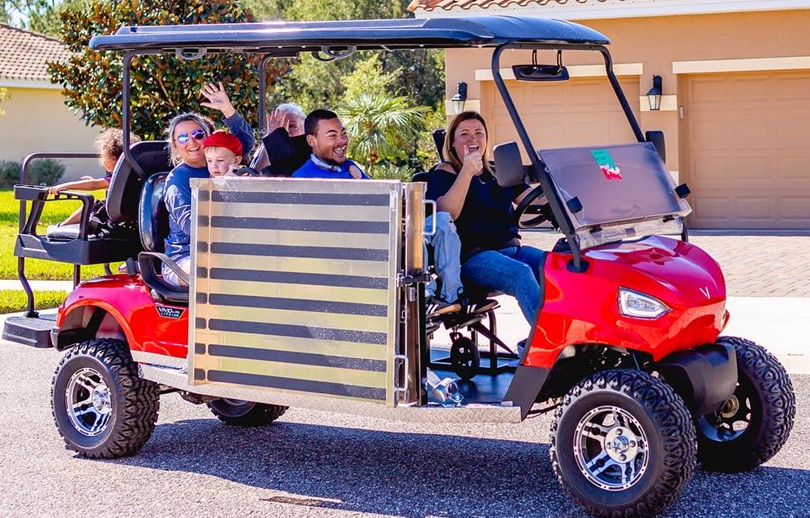 A group of people are riding in a red golf cart.