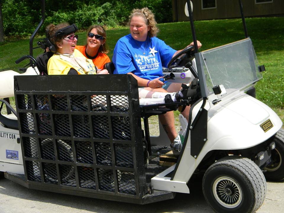 A woman in a blue shirt is driving a golf cart