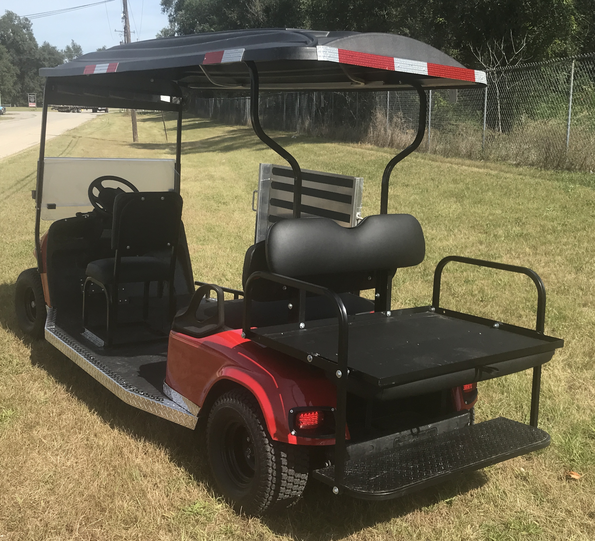 A red golf cart is parked in a grassy field