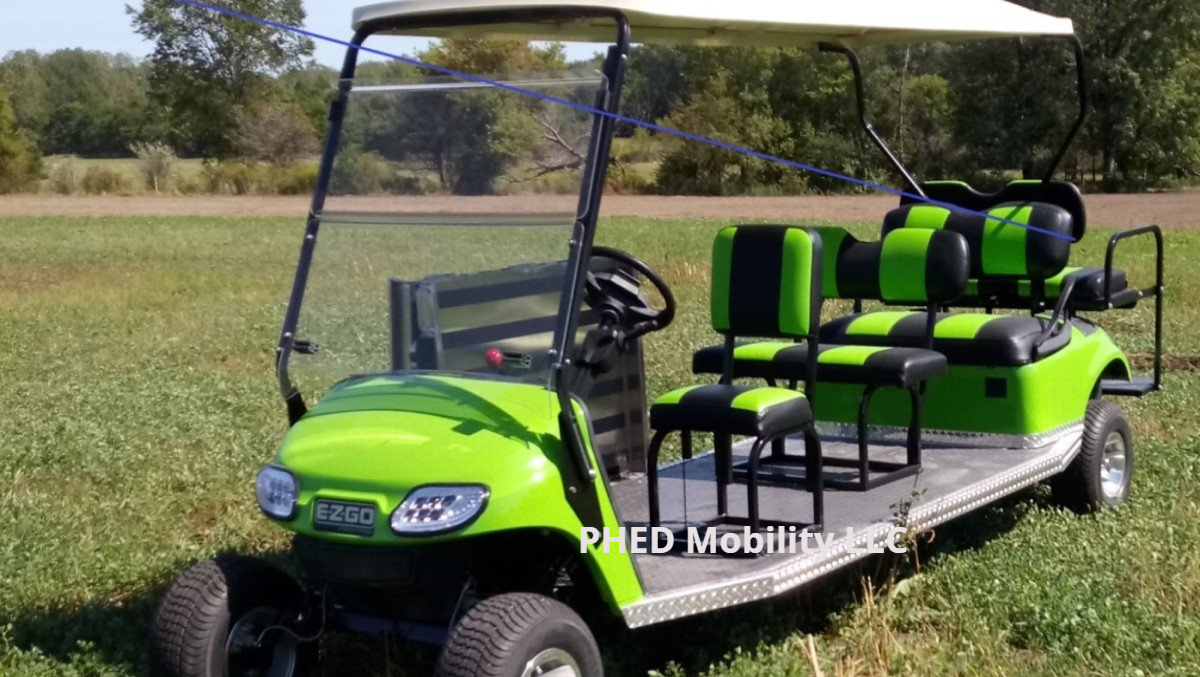 A green golf cart is parked in a grassy field.