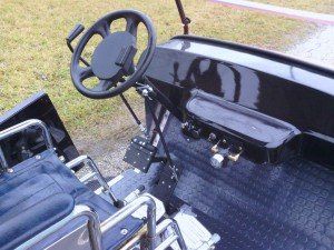 A black golf cart with a steering wheel and seats