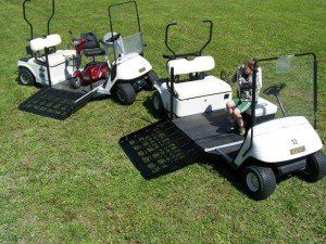 Three golf carts are parked on a lush green field