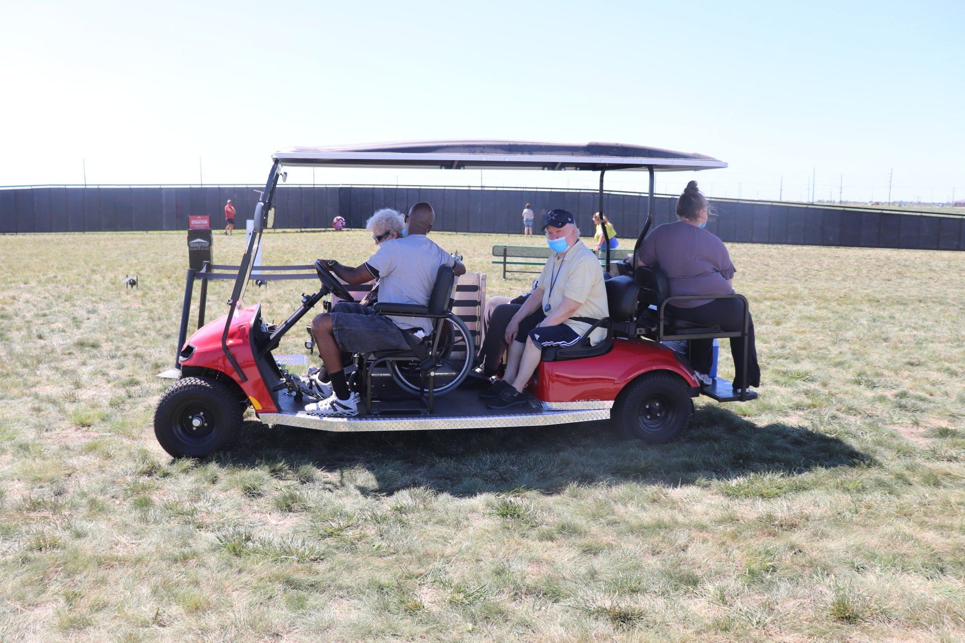 A group of people are sitting in a golf cart in a grassy field.