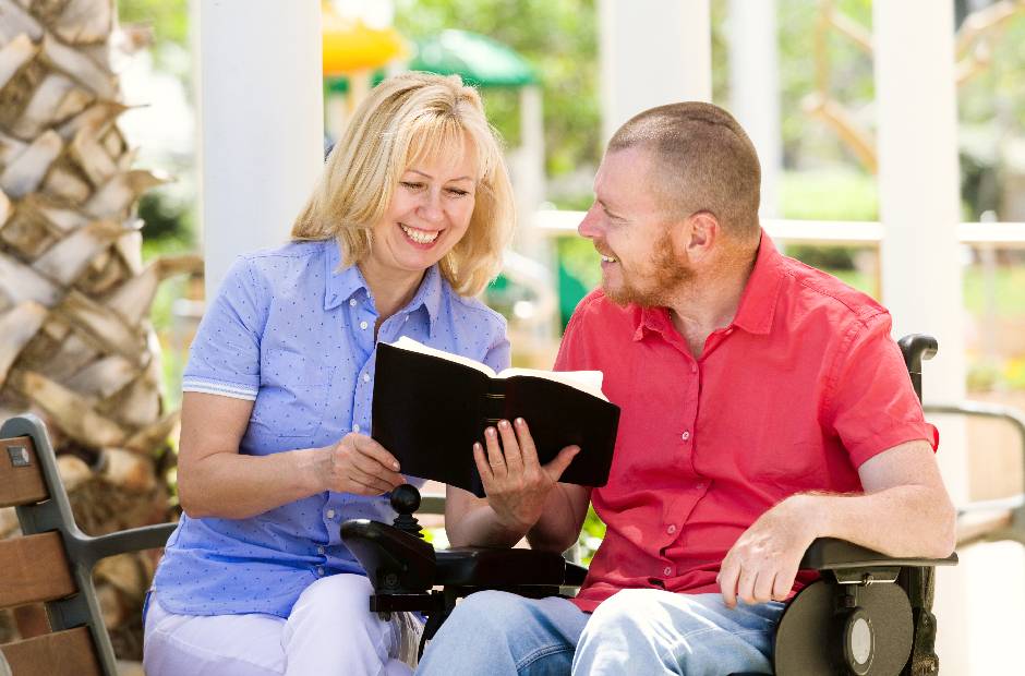 disabled man is sitting in a wheelchair and reading book