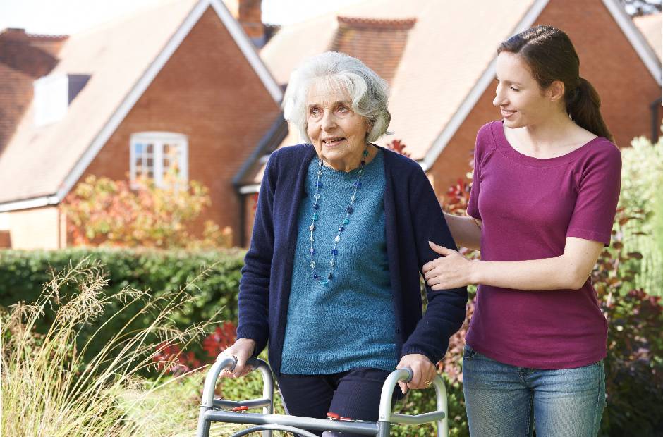 old grandmother with a walking cane walking with a lovely caregiver girl
