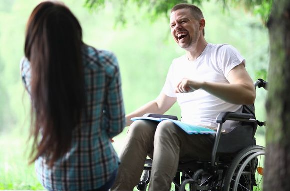 male disabled man with care taken smiling in the park