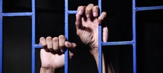 Hands hold prison bars