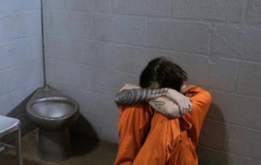 woman weeps in jail cell
