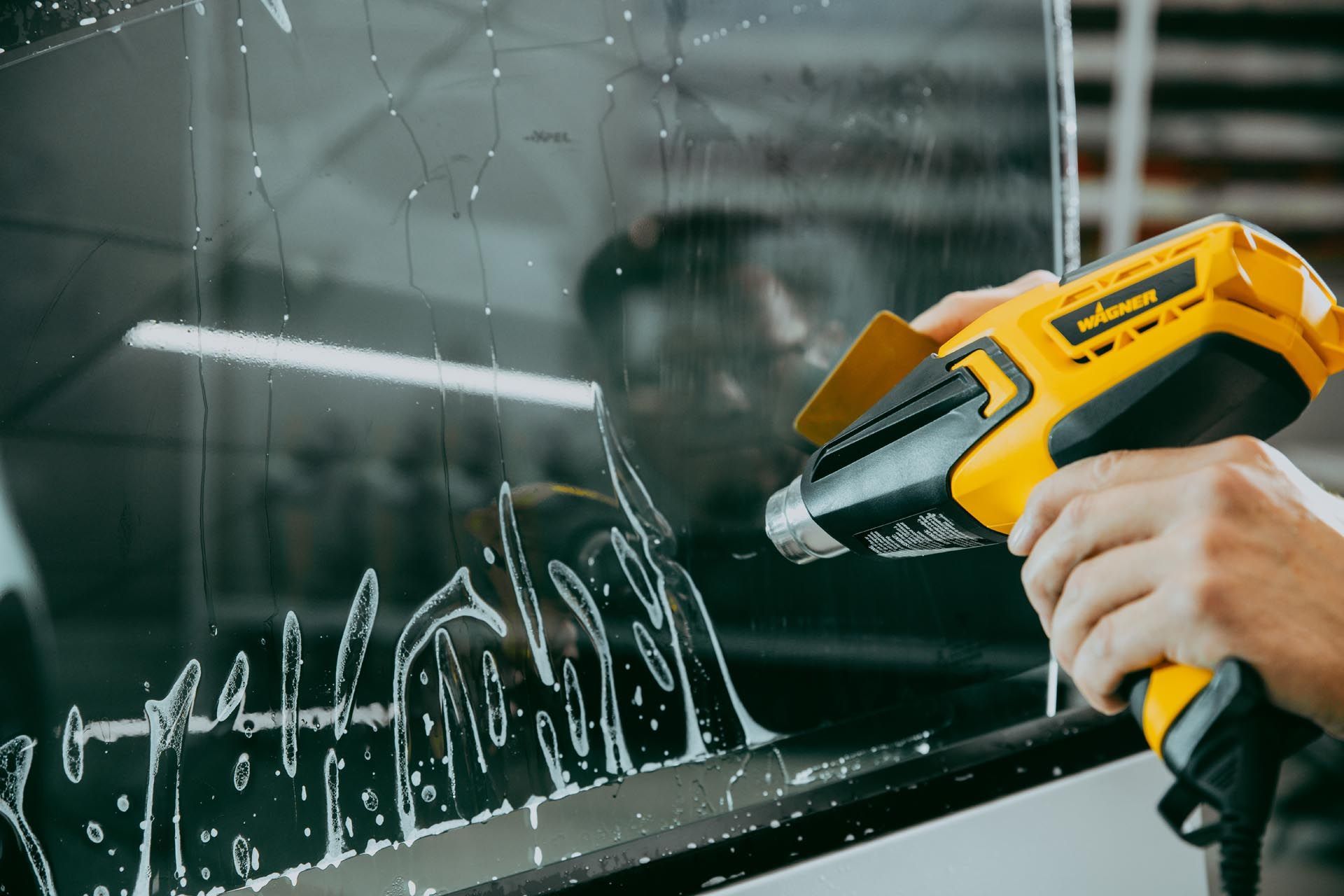 A person is wrapping a car with clear plastic