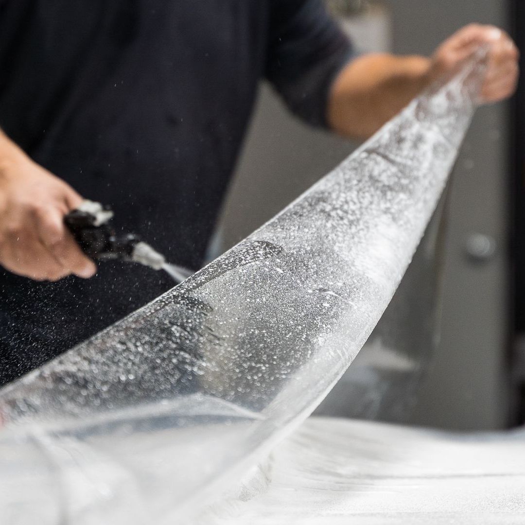 A man is cutting a large piece of ice with a pair of scissors.