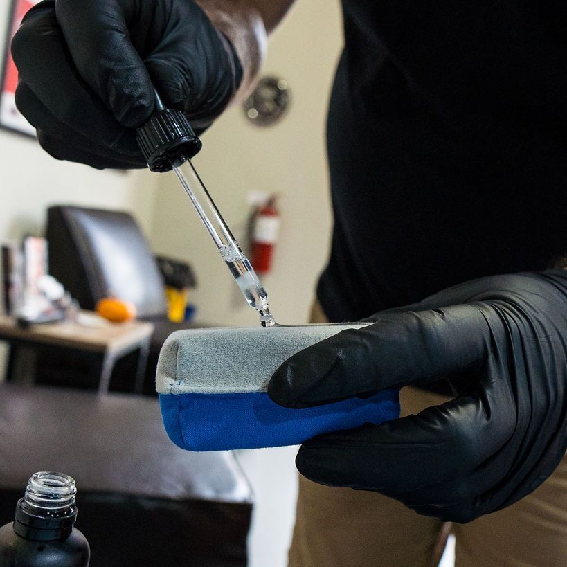 A man is applying window tinting to a car door