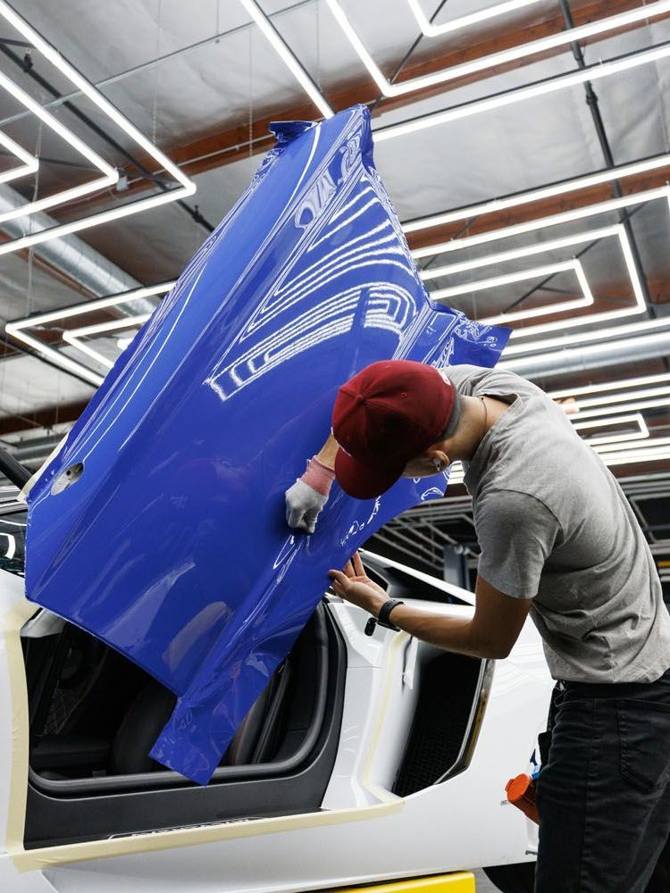 A man is working on a blue car in a garage.