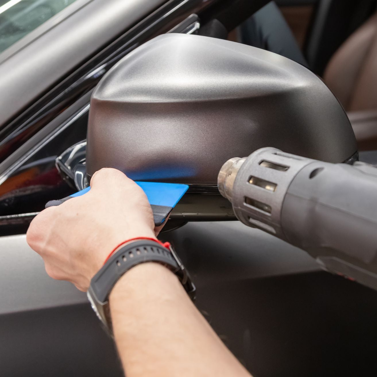 A person is wrapping a car with clear plastic