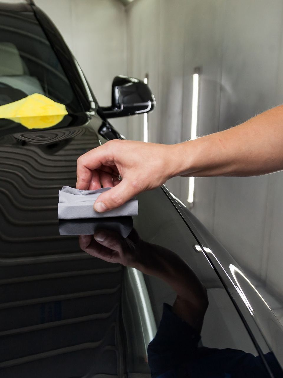 A person is polishing the hood of a black car