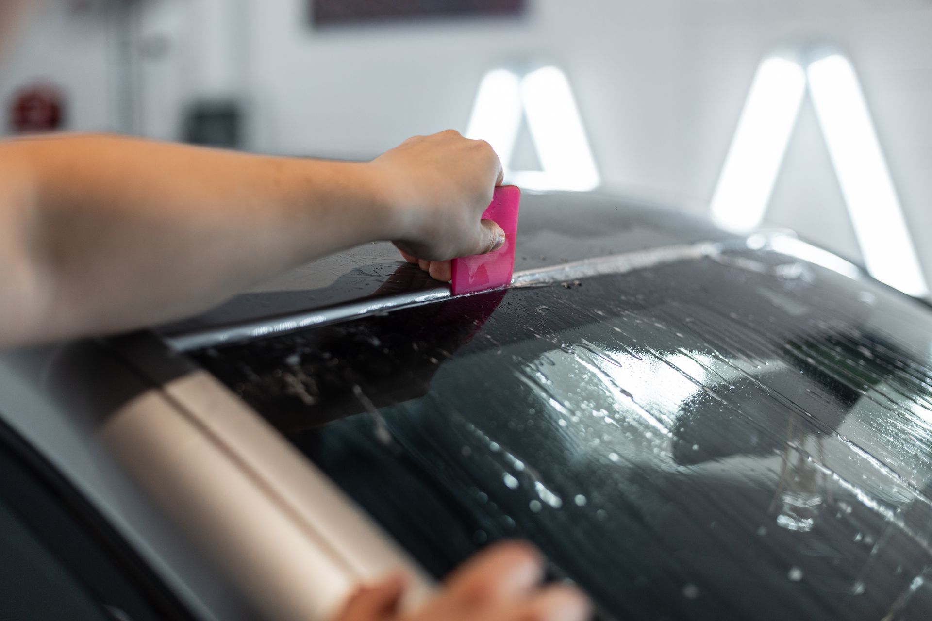 A person is cleaning the roof of a car with a squeegee.