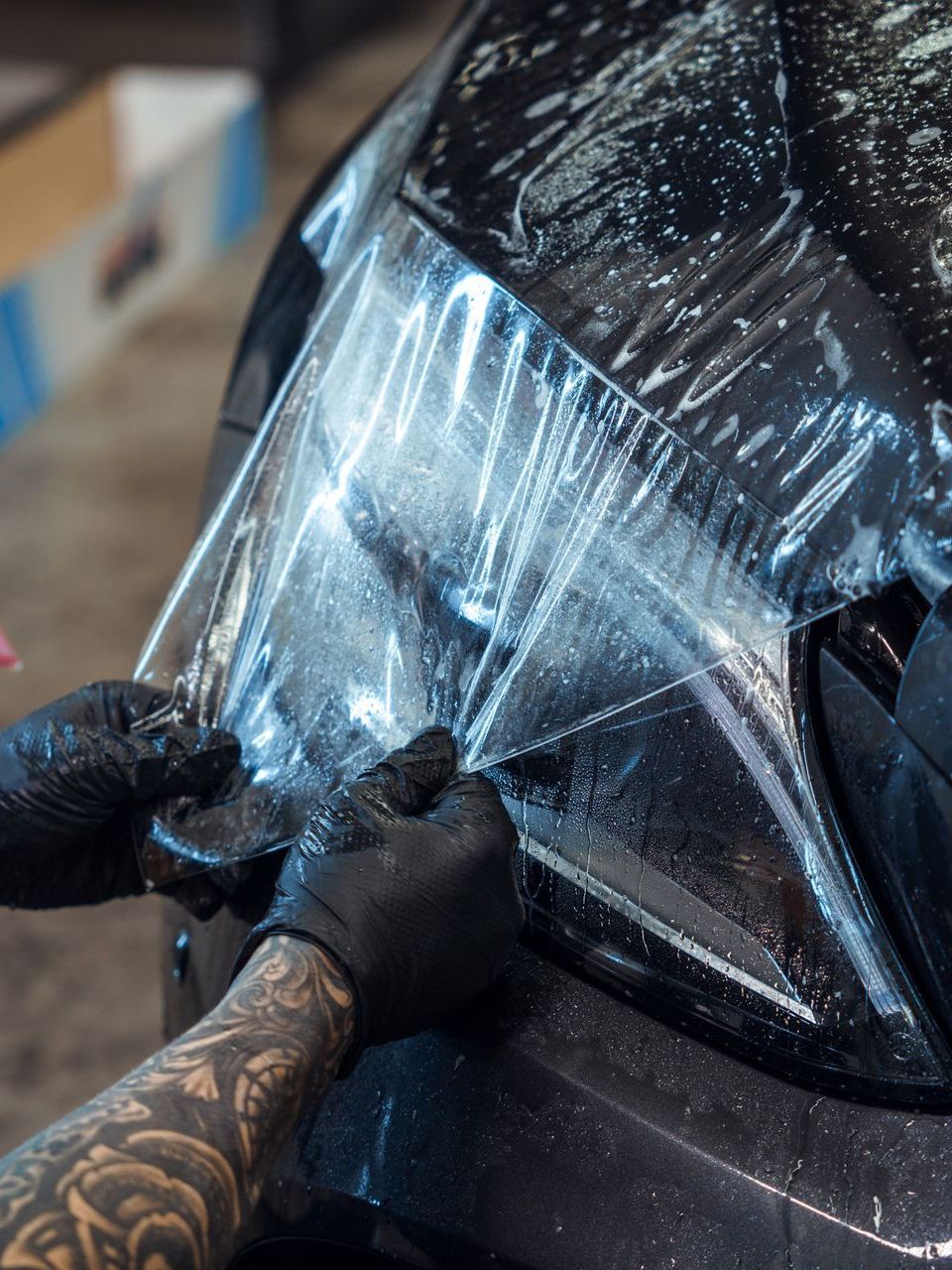 A person is wrapping a car with plastic wrap.