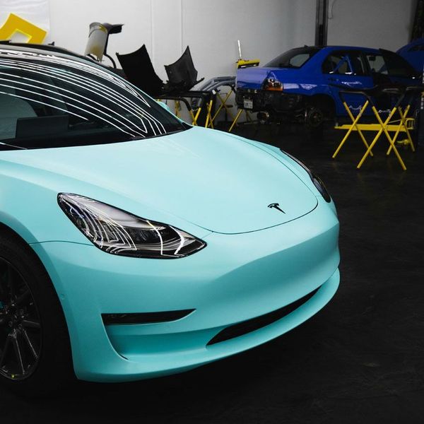 A blue tesla model 3 is parked in a garage