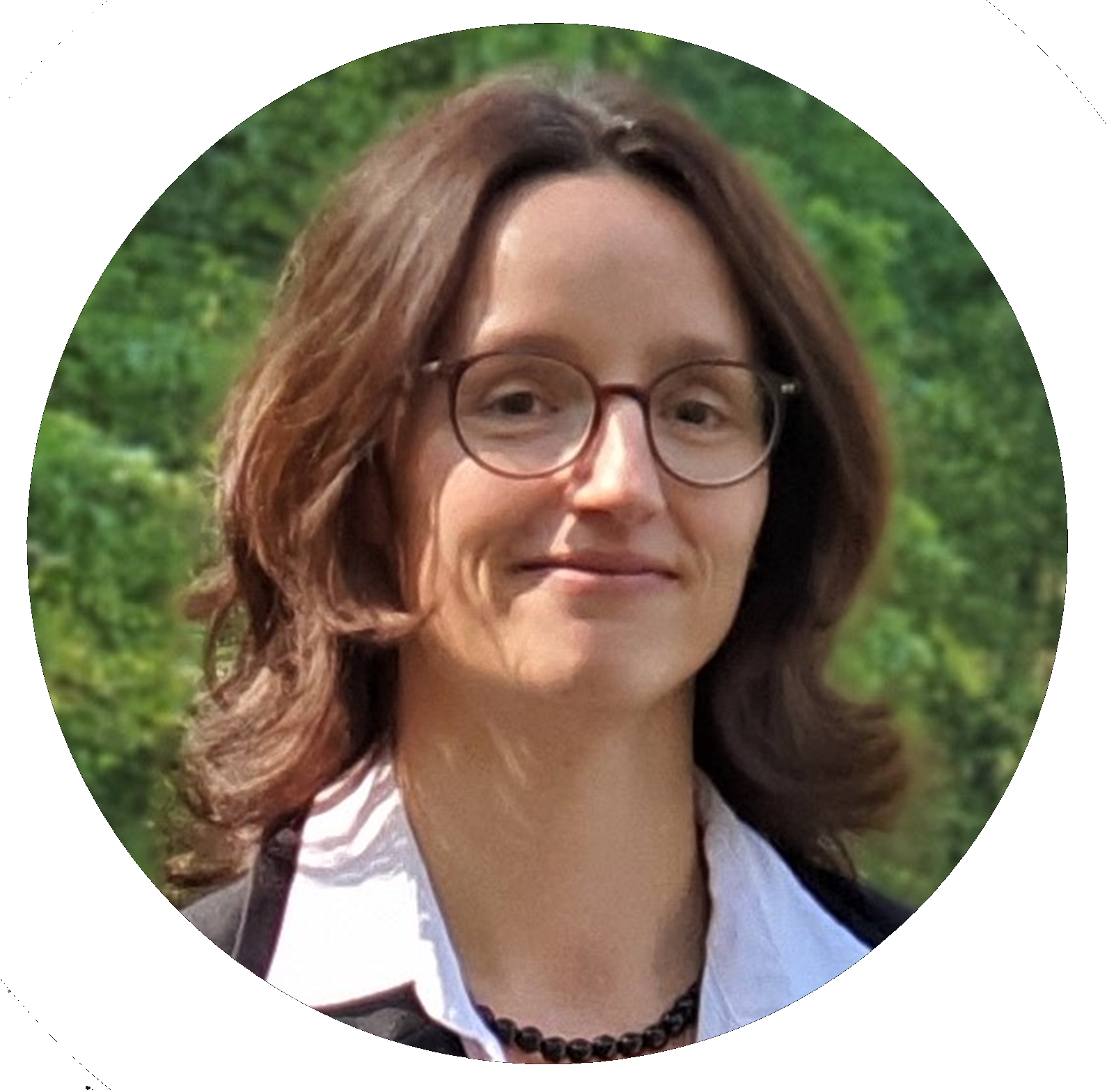 Frau mit Brille lächelt, braunes Haar, im Freien.