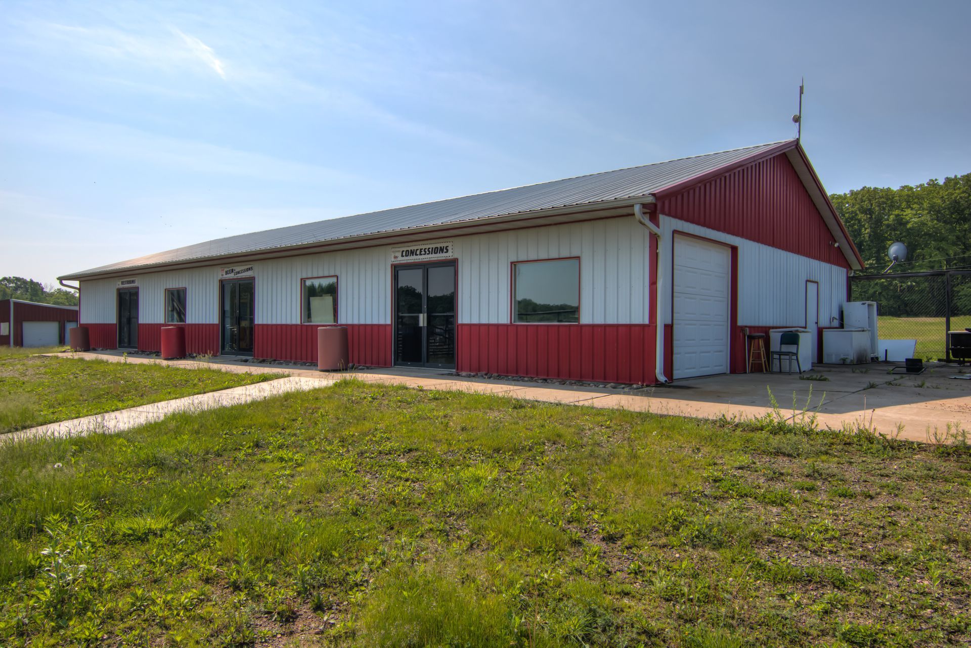 Red and white building with a metal roof. Grass in front, blue sky.