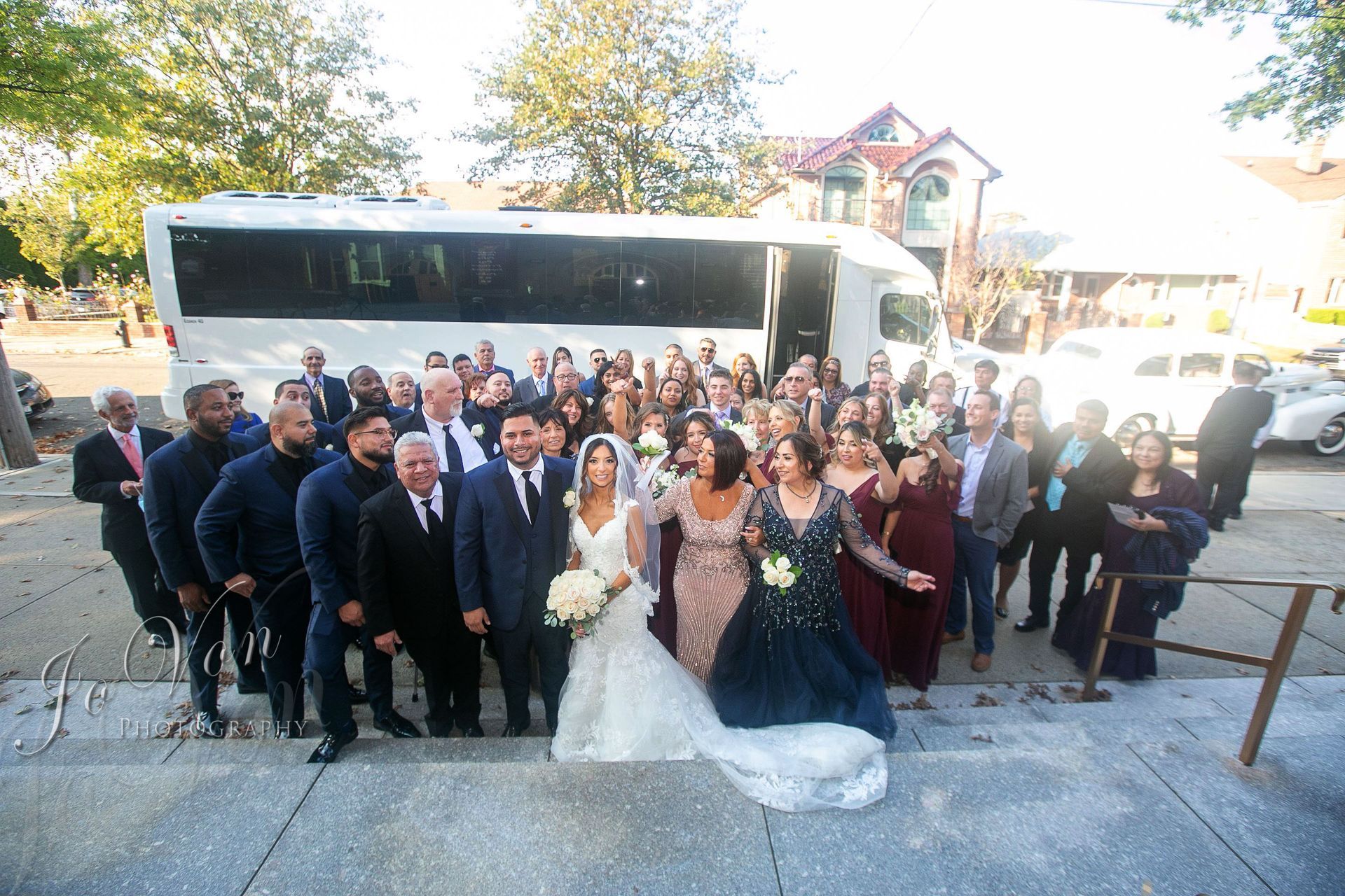 A bride and groom are sitting in the back seat of a car holding champagne glasses.