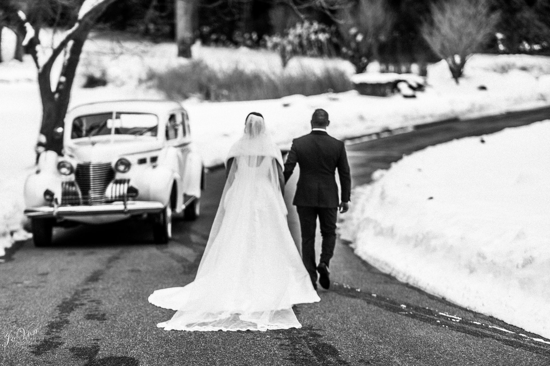 A bride and groom are sitting in the back seat of a car.