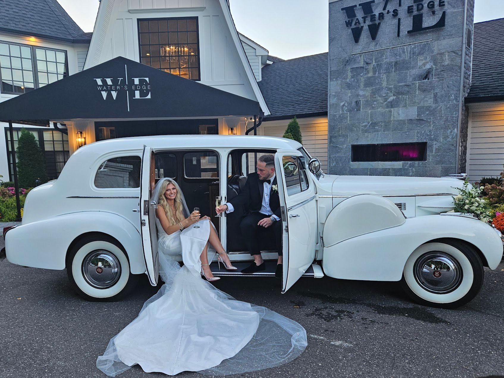 A bride and groom are sitting in a white car.