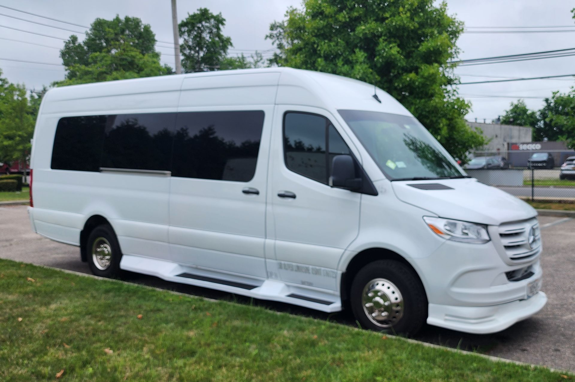 A white van is parked in a parking lot in front of a building.