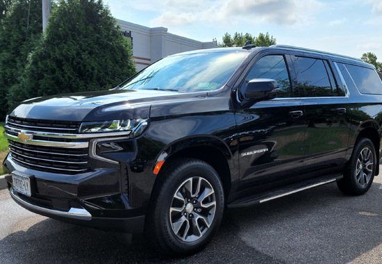 A black chevrolet suburban suv is parked in front of a building.
