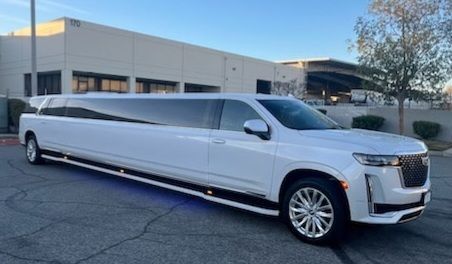 A white limousine is parked in front of a building.