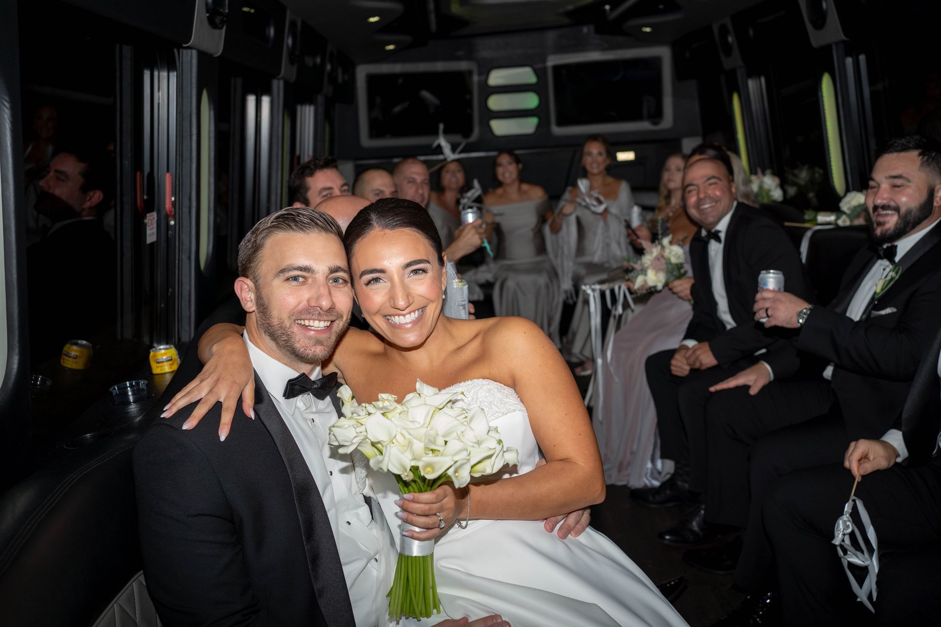 A bride and groom are posing for a picture in front of a white car.