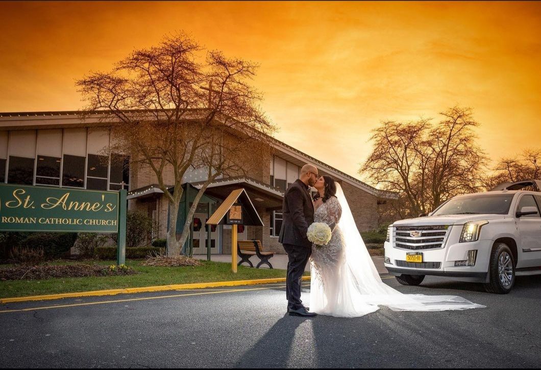 A bride and groom are posing for a picture in front of a white limousine.