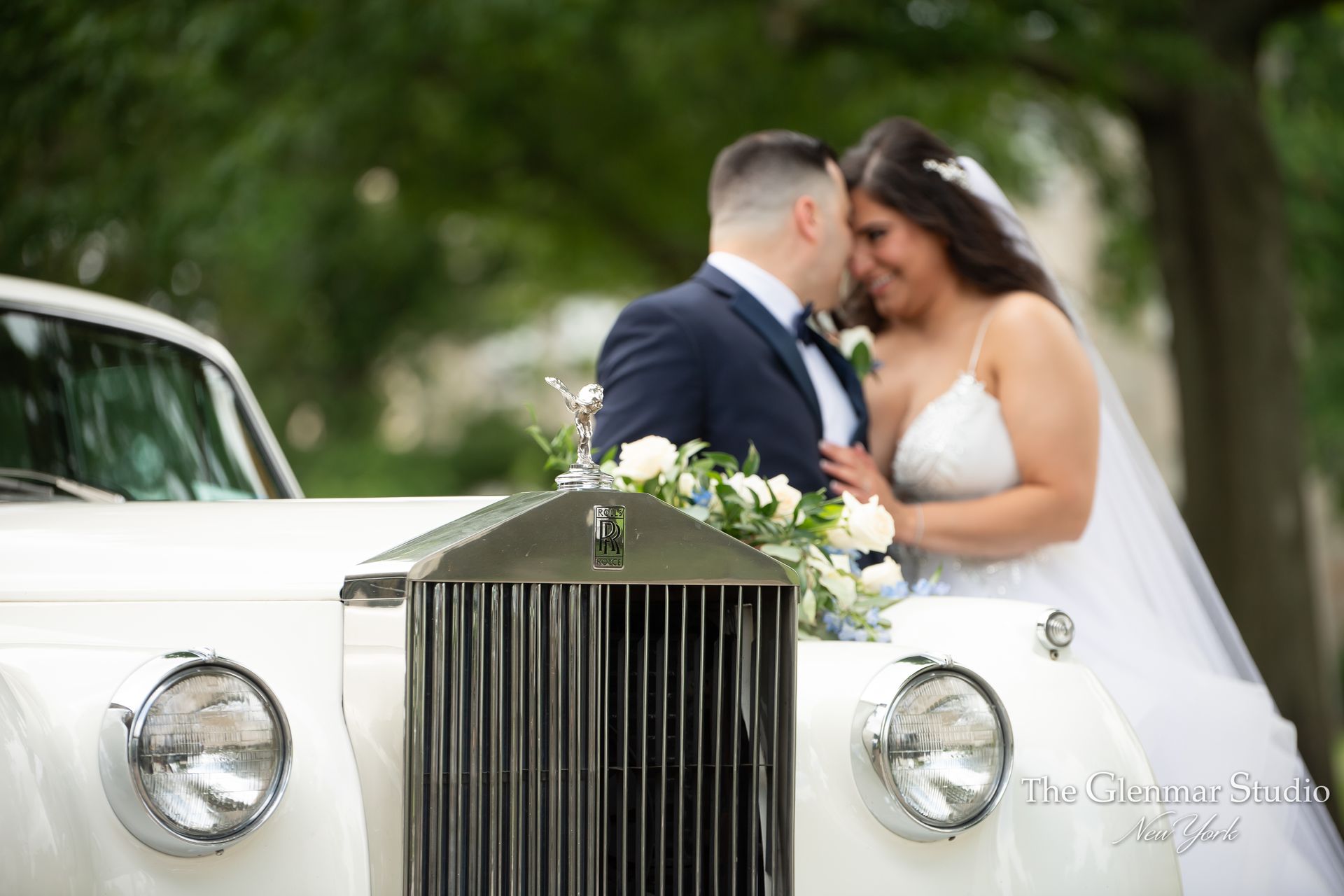 A bride and groom are sitting in a white car.