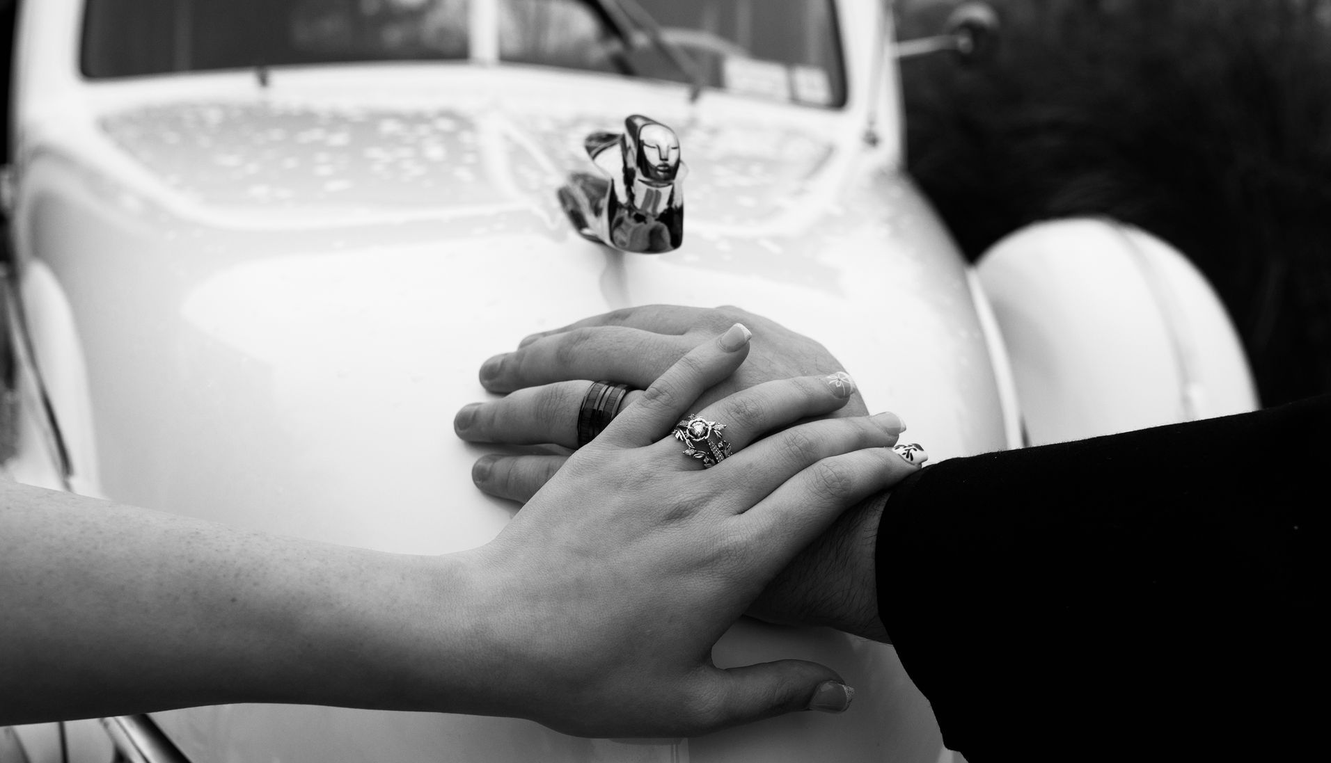 A bride and groom are holding hands in front of a white car.