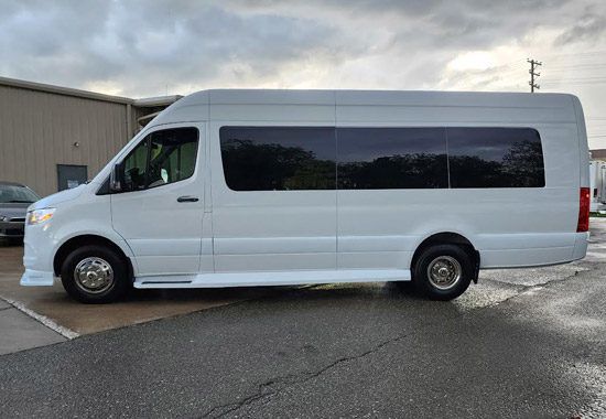 A white van is parked in a parking lot in front of a building.