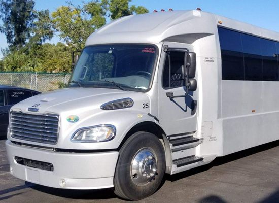 A white bus with the number 25 on the front is parked in a parking lot.