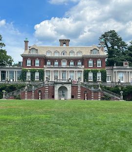 A large brick building with stairs leading up to it is sitting on top of a lush green field.