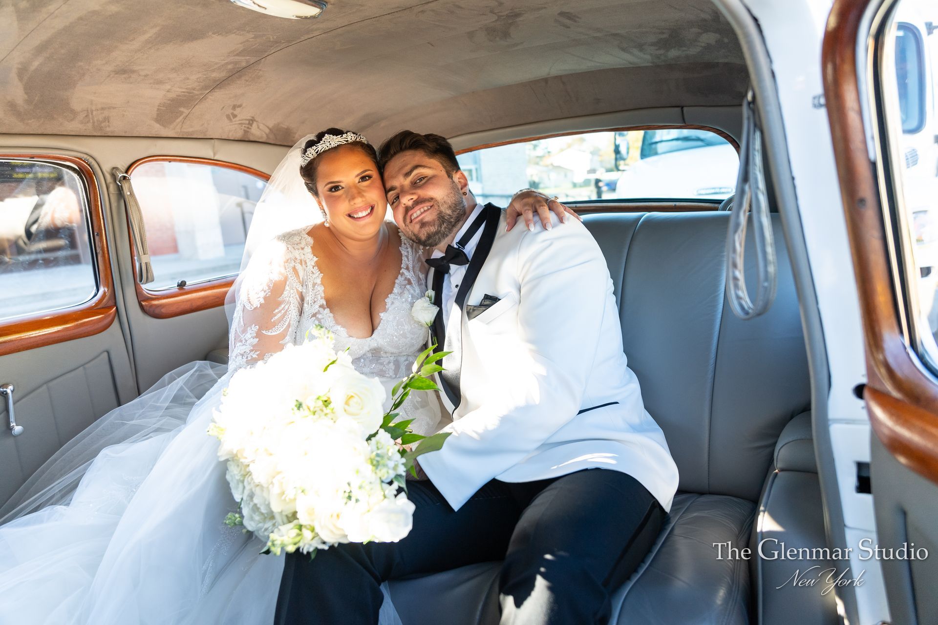 A bride and groom are sitting in the back seat of a car.