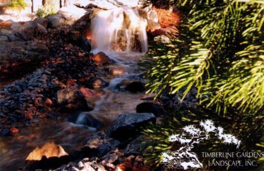 Waterfall cascading over rocks in a garden, with a blurred effect on the water.